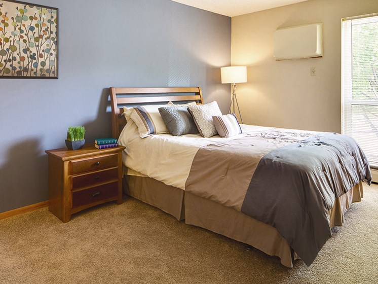 Bedroom with a bed with gray, brown, and white large stripped pattern comforter
